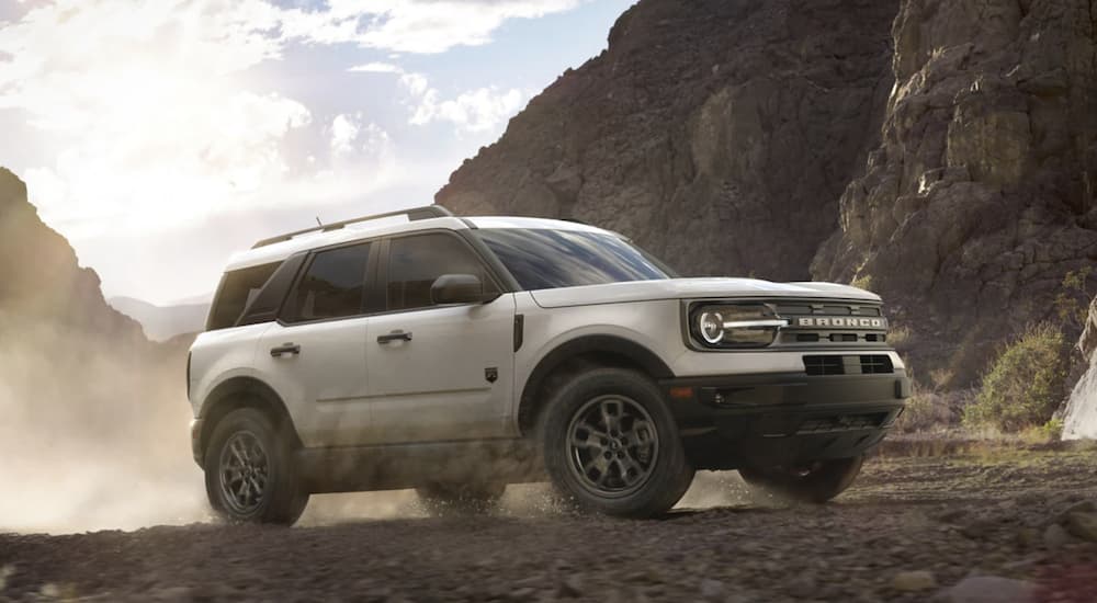 A white 2022 Ford Bronco Sport is shown from the side off-roading in the mountains.
