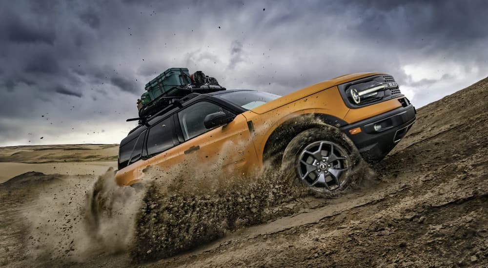 A yellow 2022 Ford Bronco Sport is shown driving on a dirt hill.