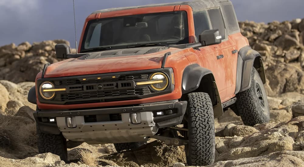 An orange 2022 Ford Bronco is shown off-roading after researching 2022 Ford Bronco sales.