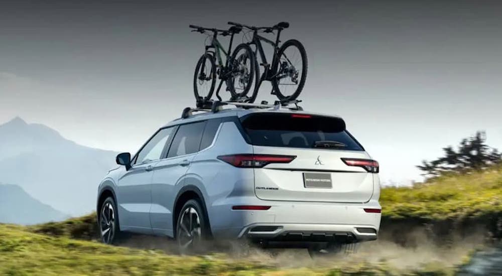 A white 2022 Mitsubishi Outlander is shown from the back off-road while loaded with bikes.