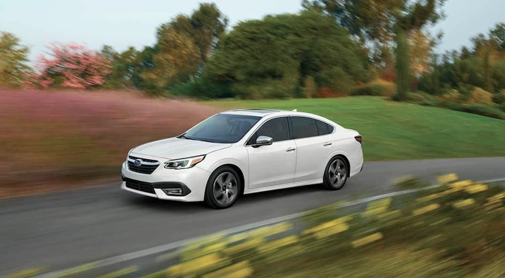 A white 2022 Subaru Legacy Touring XT is shown from the side driving on an open road.