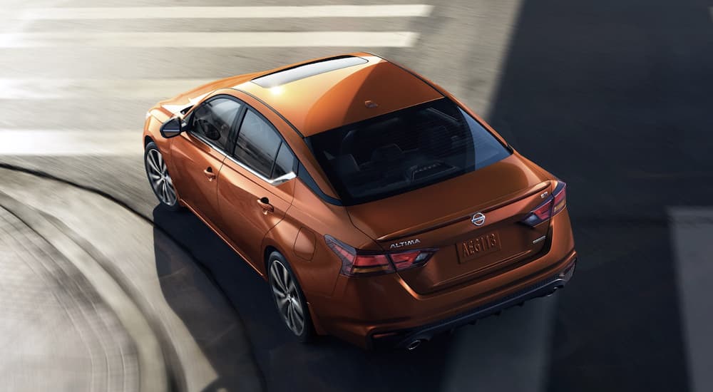 An orange 2022 Nissan Altima is shown from above rounding a city corner.