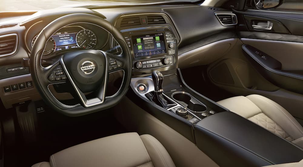 The brown interior of a 2022 Nissan Maxima shows the steering wheel and infotainment screen.