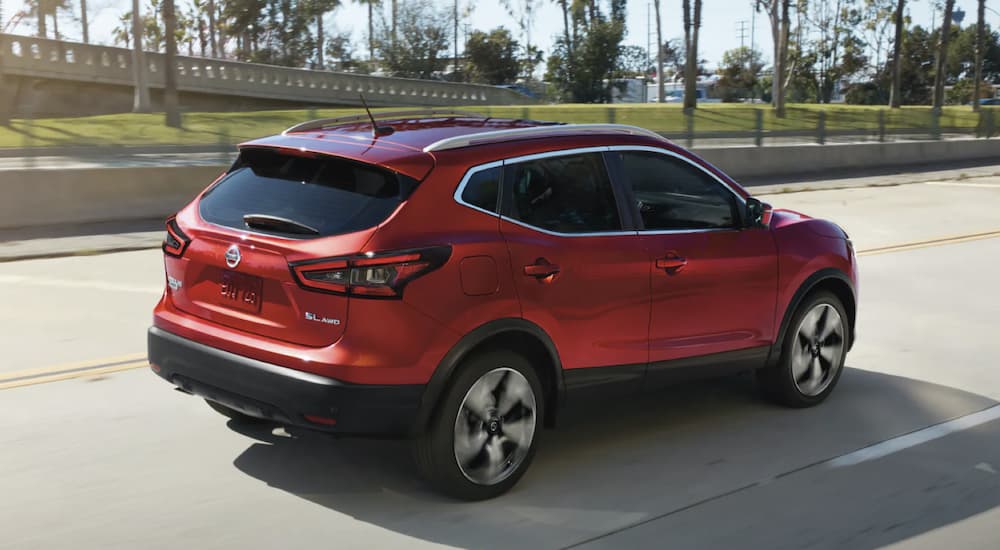 A red 2022 Nissan Rogue Sport is shown from the side driving on an open road.