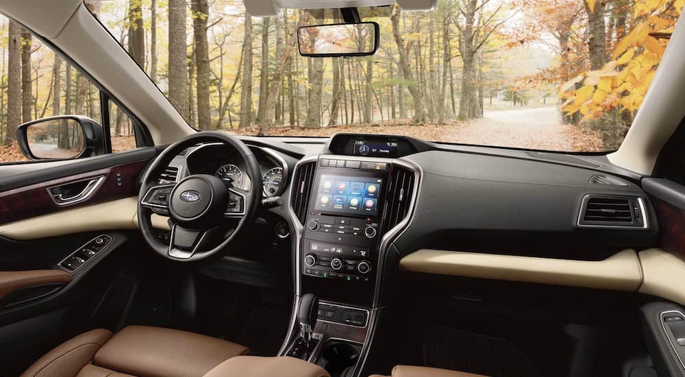 The black interior of a 2022 Subaru Ascent Touring shows the steering wheel and infotainment screen.