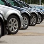 A line of cars is shown parked at an angle at a dealership.