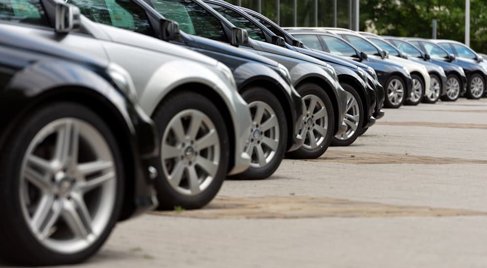 A line of cars is shown parked at an angle at a dealership.