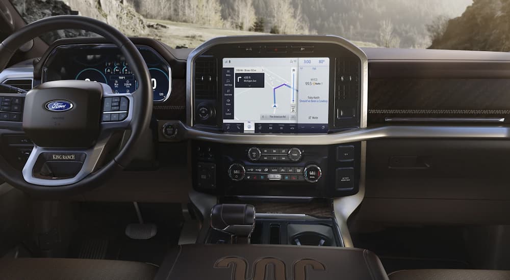The black interior of a 2022 Ford F-150 King Ranch shows the steering wheel and infotainment screen.