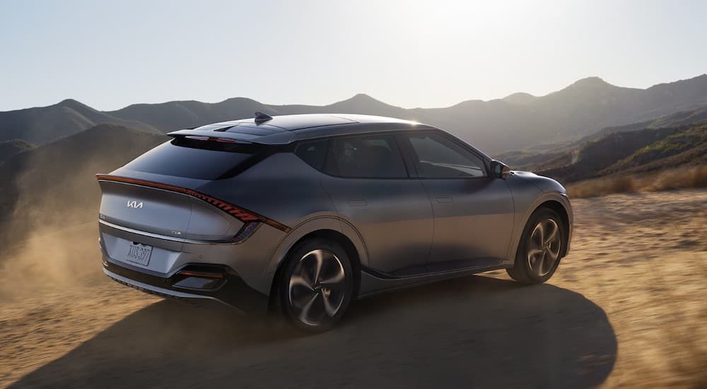 A grey 2022 Kia EV6 is shown from behind at an angle while it drives over dirt.