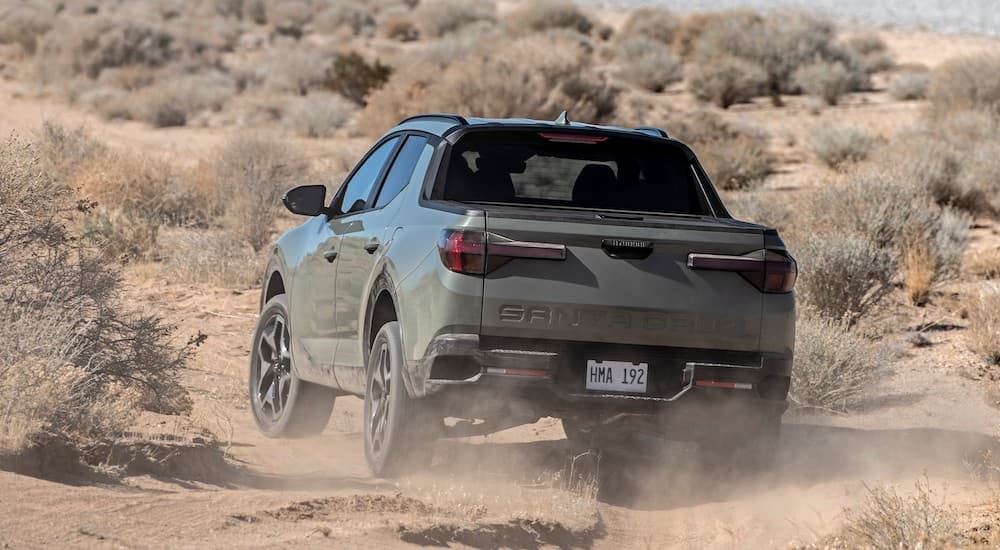 A grey 2022 Hyundai Santa cruise is shown from the rear while it drives off-road after leaving a Hyundai Dealer in Edmonton.