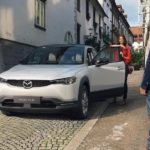 A white 2022 Mazda MX-30 is shown in an alleyway after visiting a Mazda dealer near you.