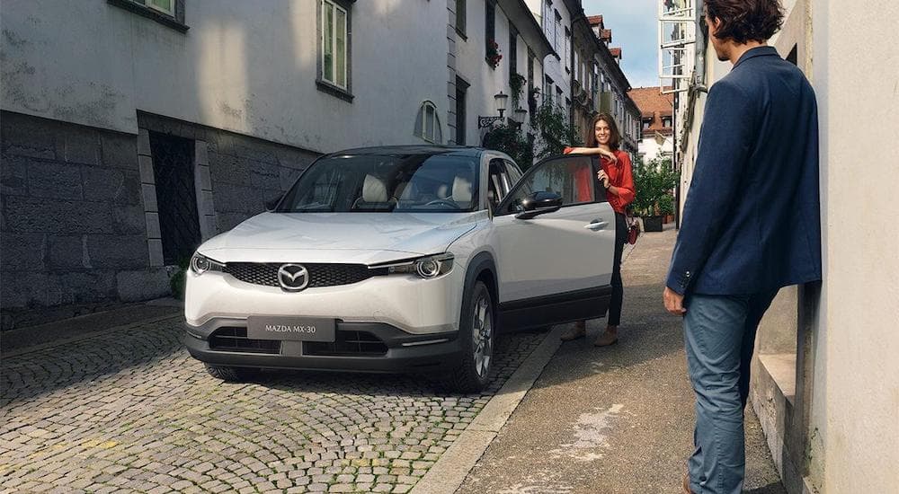 A white 2022 Mazda MX-30 is shown in an alleyway after visiting a Mazda dealer near you.