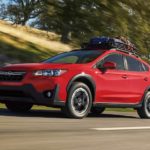 A red 2022 Subaru Crosstrek Premium is shown driving on an empty road after leaving a Subaru dealer near you.