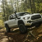 A white 2022 Toyota Tacoma TRD Pro is shown from the front while it drives off-road after leaving a Tuckahoe Toyota dealership.