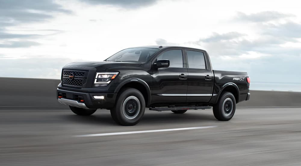 A black 2022 Nissan Titan is shown from the side while it drives down the road.