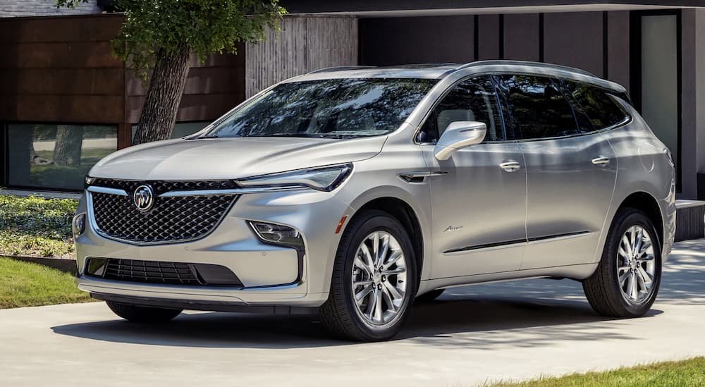 A silver 2022 Buick Enclave is angled left parked in front of a modern building.