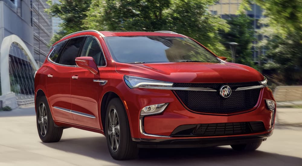 A red 2022 Buick Enclave is shown from the front parked in front of a modern building.