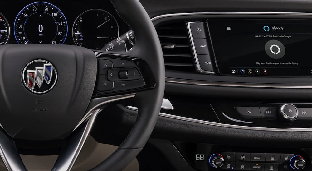 The black interior of a 2022 Buick Enclave shows the steering wheel and infotainment screen.