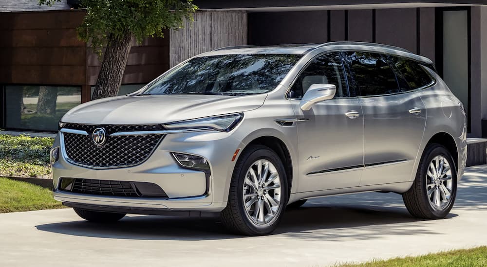 A silver 2022 Buick Enclave is shown parked in front of a modern house during a 2022 Buick Enclave vs 2022 Dodge Durango comparison.