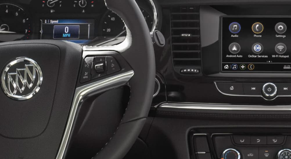The black interior of a 2022 Buick Encore shows the steering wheel and infotainment screen.