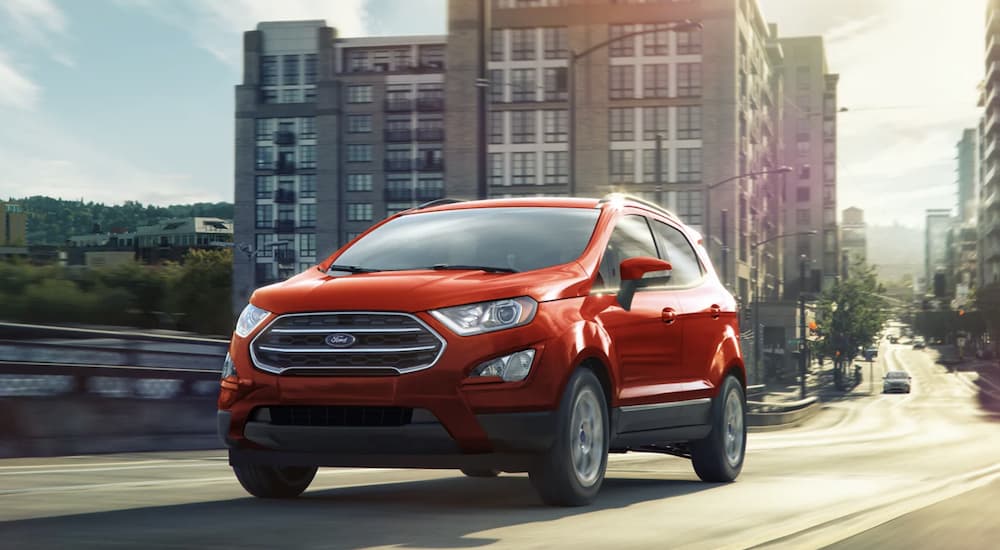 A red 2022 Ford EcoSport is shown from the front driving through a city.