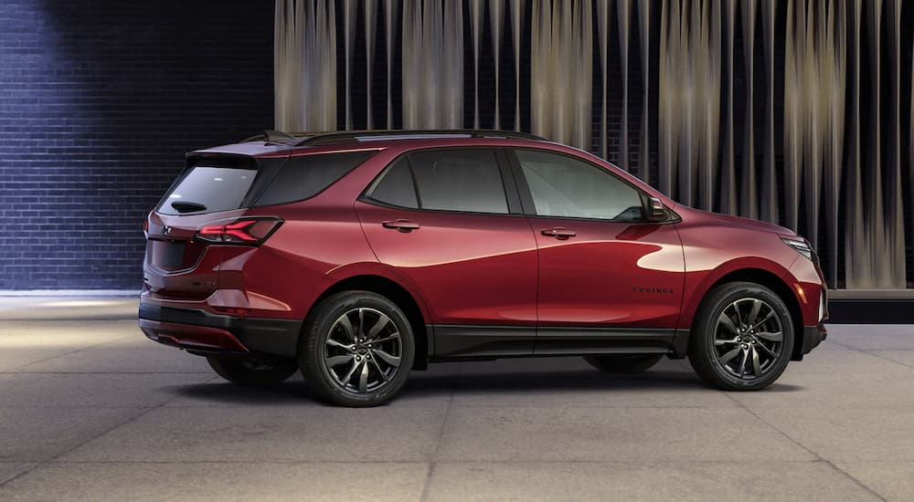 A red 2022 Chevy Equinox is shown from the side parked in a gallery during a 2022 Chevy Equinox vs 2022 Ford Escape comparison.