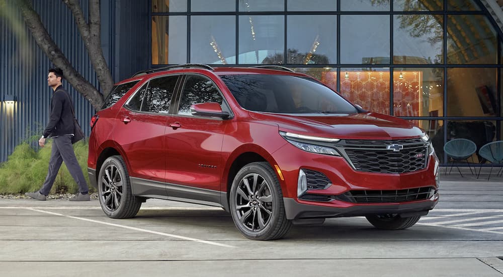 A red 2022 Chevy Equinox is shown from the side parked in front of a glass building.