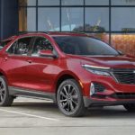 A red 2022 Chevy Equinox is shown from the front parked in front of a modern building during a 2022 Chevy Equinox vs 2022 Mitsubishi Eclipse Cross comparison.