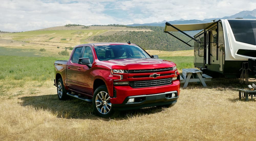A red 2022 Chevy Silverado 1500 is shown from the front parked next to a trailer during a 2022 Chevy Silverado 1500 vs 2022 Ford F-150 comparison.