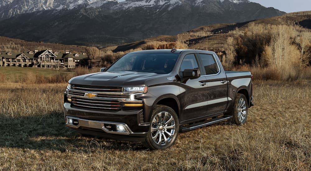 A black 2022 Chevy Silverado 1500 High Country is shown from the side parked in a field.