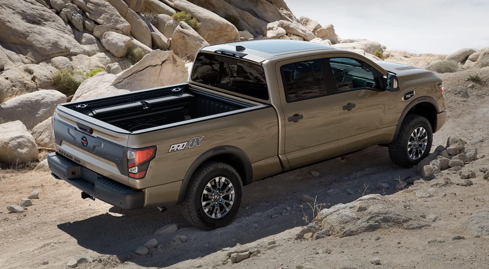 A tan 2022 Nissan Titan is shown from the side off-roading in the mountains.