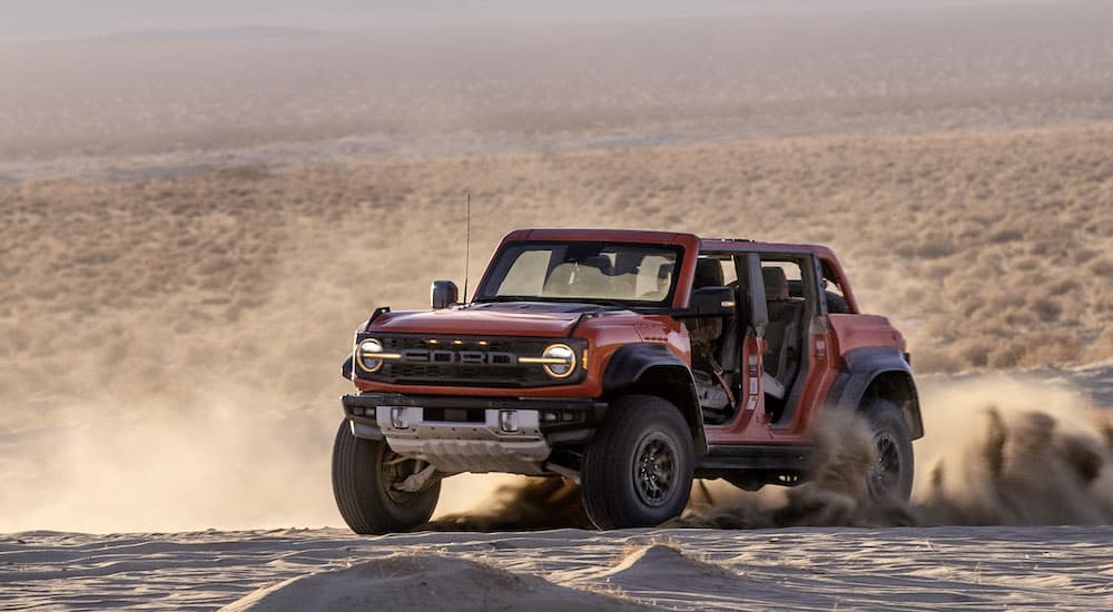 A red 2022 Ford Bronco Raptor is shown from the front at an angle while sliding.