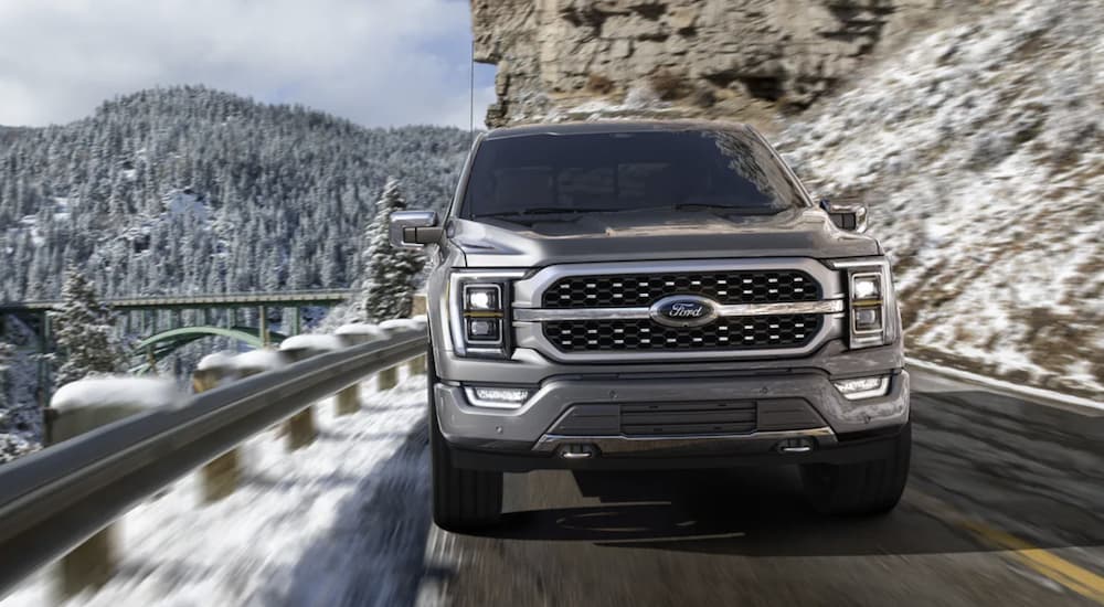 A grey 2022 Ford F-150 is shown from the front driving in the mountains during a 2022 Ford F-150 vs 2022 Nissan Titan comparison.
