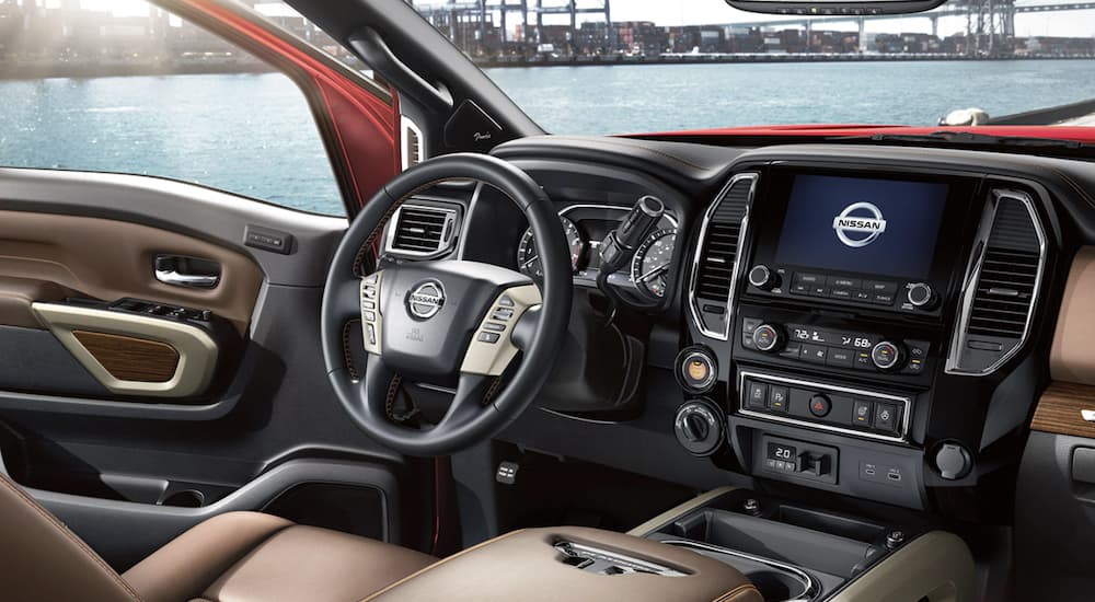 The black and brown interior of a 2022 Nissan Titan shows the steering wheel and infotainment screen.