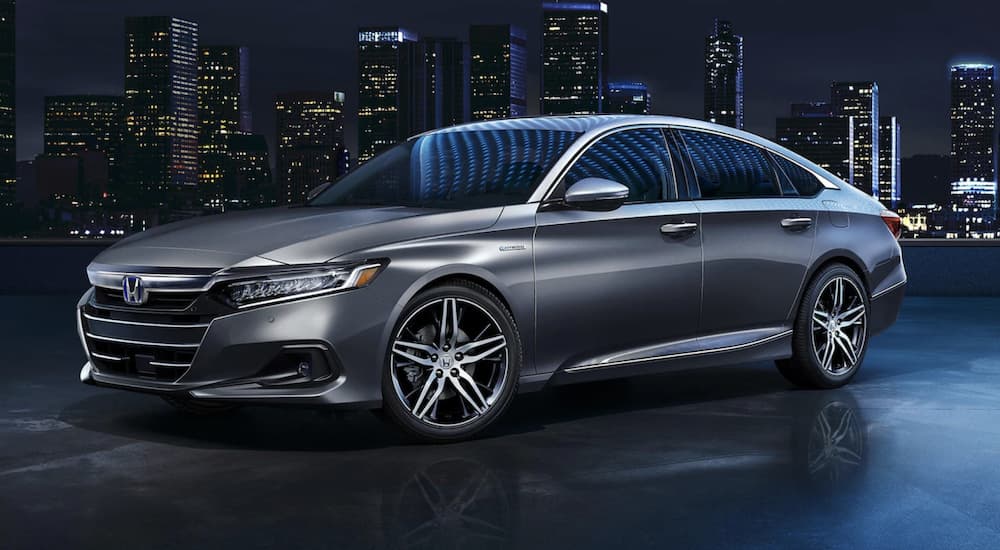 A silver 2022 Honda Accord Hybrid Touring is shown from the side parked in a city at night.