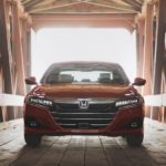 A red 2022 Honda Accord Touring 2.0T is shown from the front parked inside a covered bridge during a 2022 Honda Accord vs 2022 Nissan Altima comparison.