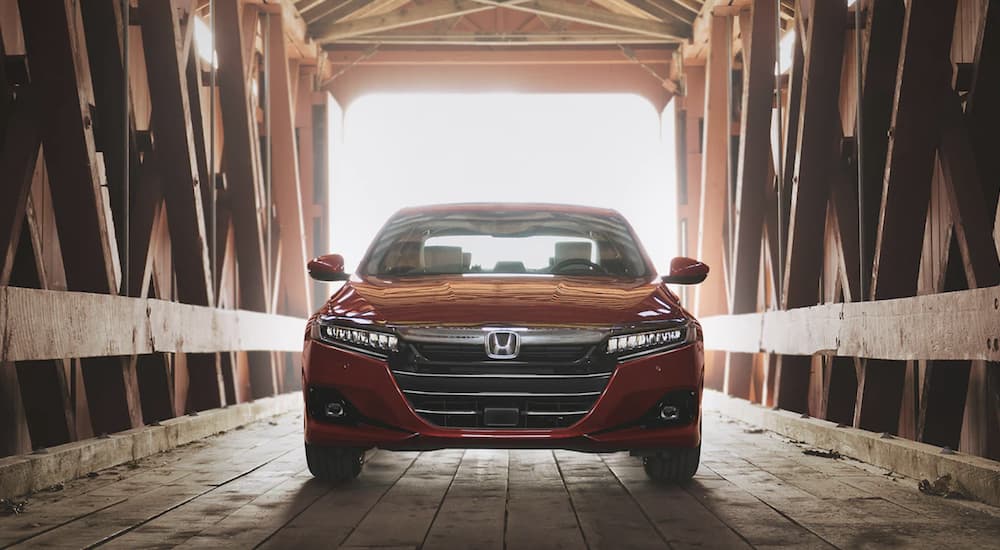 A red 2022 Honda Accord Touring 2.0T is shown from the front parked inside a covered bridge during a 2022 Honda Accord vs 2022 Nissan Altima comparison.