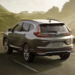 A grey 2022 Honda CR-V Hybrid Touring is shown from the rear driving on a paved road.