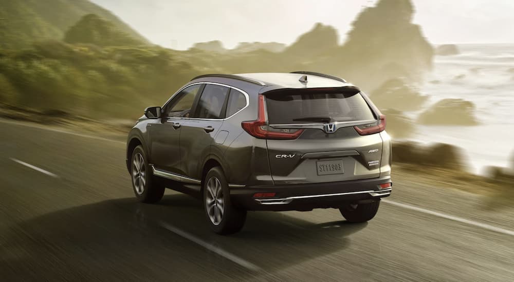 A grey 2022 Honda CR-V Hybrid Touring is shown from the rear driving on a paved road.