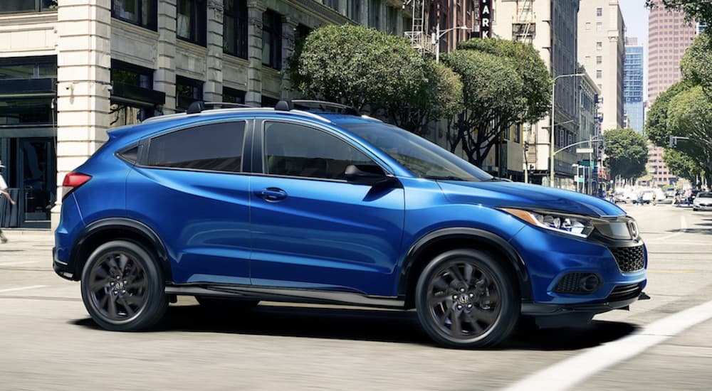 A blue 2022 Honda HR-V Sport is shown from the side driving through a city.