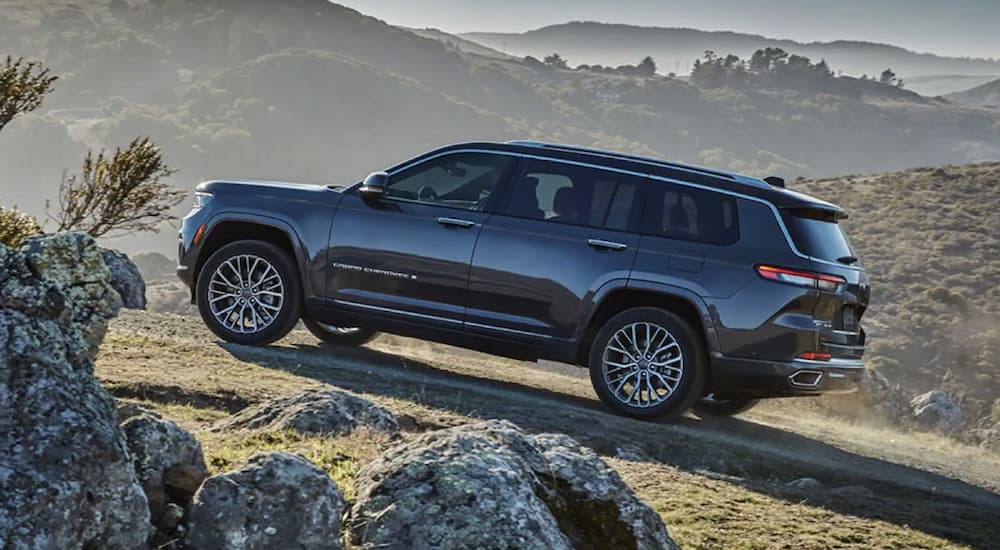 A black 2022 Jeep Grand Cherokee is shown from the side parked in the mountains.