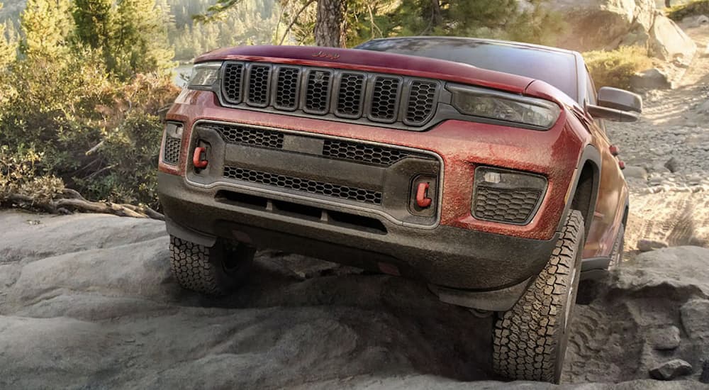 A red 2022 Jeep Grand Cherokee is shown from the front parked on a steep rock.