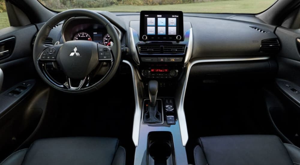 The black interior of a 2022 Mitsubishi Eclipse Cross shows the steering wheel and infotainment screen.
