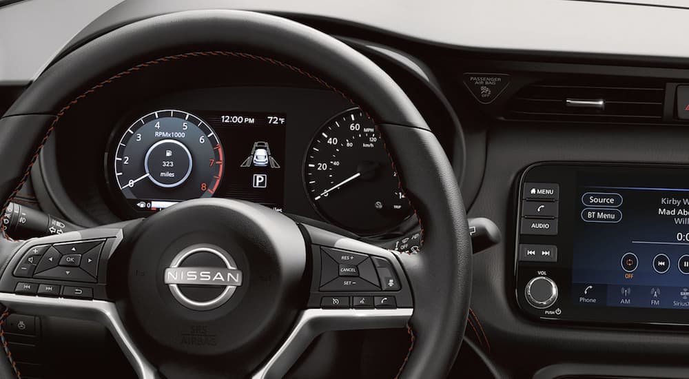 The black interior of a 2022 Nissan Kicks shows the steering wheel and infotainment screen.