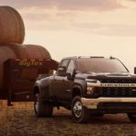 A black 2022 Silverado 3500 HD is shown towing a trailer full of hay.