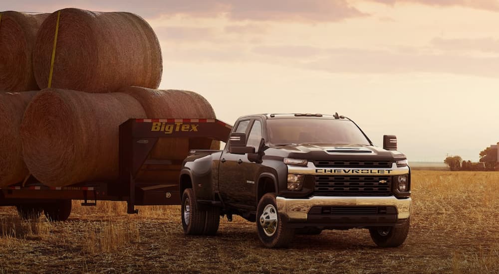 A black 2022 Silverado 3500 HD is shown towing a trailer full of hay.