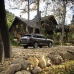 A dark grey 2022 Subaru Outback XT is shown parked outside a cabin in the woods.
