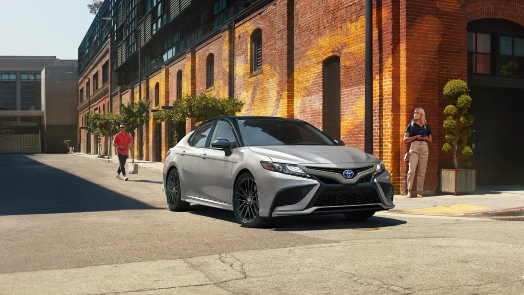 A silver 2022 Toyota Camry XSE Hybrid is shown driving on a city street.