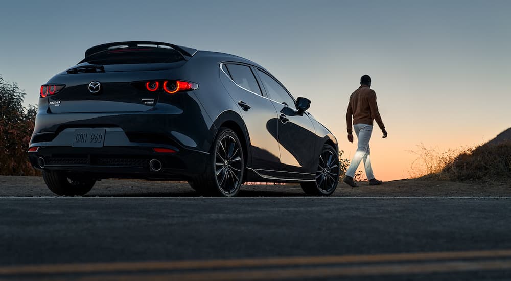 A black 2022 Mazda3 is shown from the rear at an angle at dusk.