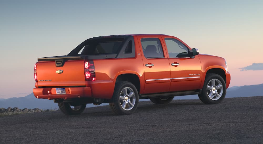 An orange 2011 Chevy Avalanche LTZ is shown from the side against a cloudy background.